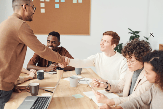 man shaking hands with business people